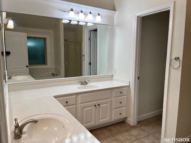 full bath with tile patterned floors, a sink, a shower stall, and double vanity