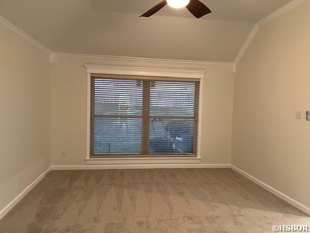 carpeted empty room with ceiling fan, baseboards, vaulted ceiling, and crown molding