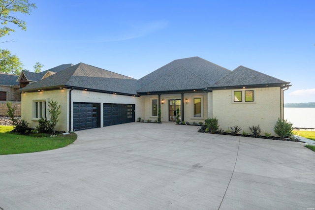 view of front facade featuring concrete driveway, a garage, brick siding, and a shingled roof