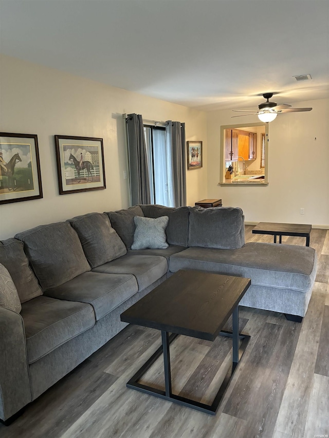 living area with dark wood-type flooring, visible vents, and a ceiling fan