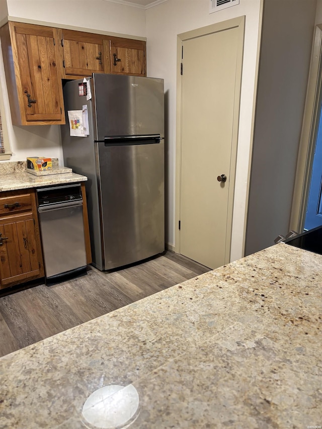 kitchen featuring light wood finished floors, light countertops, visible vents, brown cabinetry, and freestanding refrigerator