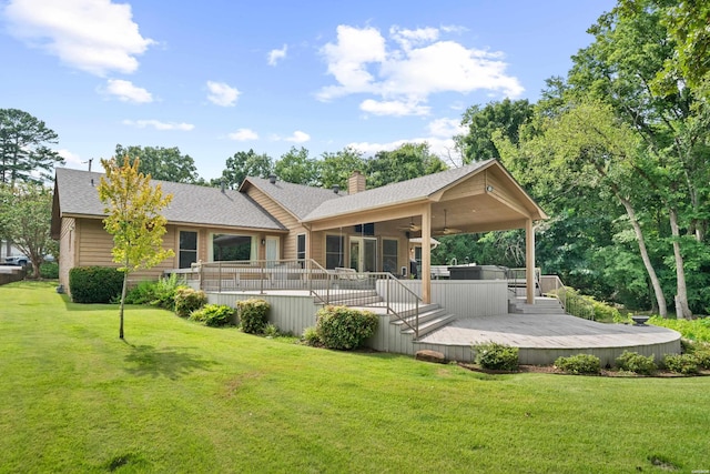 back of property with a yard, ceiling fan, a chimney, and a wooden deck