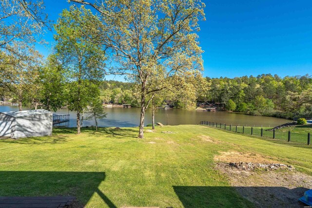 view of yard with a storage unit, a water view, and fence