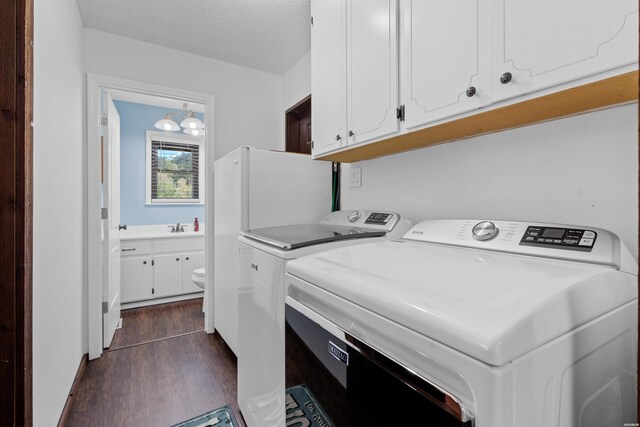 washroom featuring washing machine and clothes dryer, cabinet space, dark wood-type flooring, a sink, and a textured ceiling