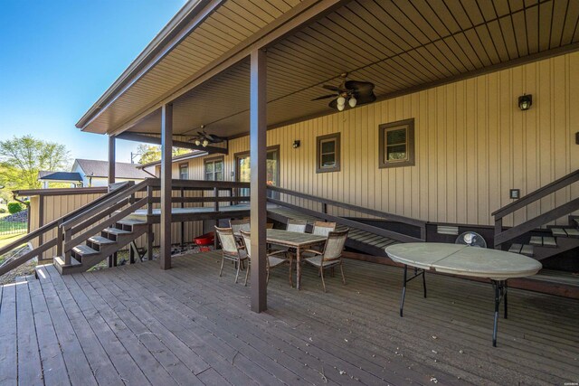 wooden terrace featuring outdoor dining area, stairway, and a ceiling fan