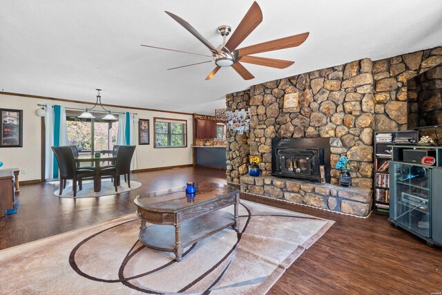 living area with baseboards, ceiling fan, dark wood-style flooring, crown molding, and a textured ceiling