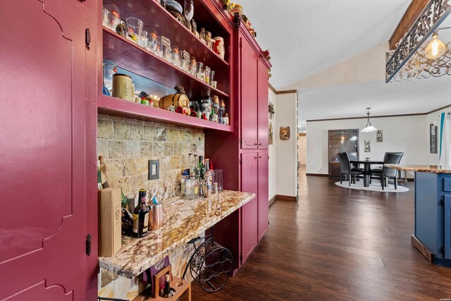 bar with lofted ceiling, hanging light fixtures, backsplash, dark wood-type flooring, and a bar