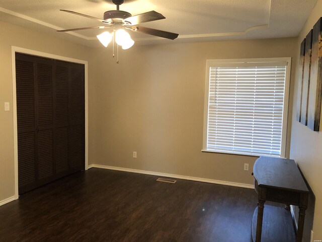 unfurnished bedroom with dark wood-style flooring, a closet, visible vents, and baseboards