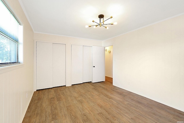1405 Emory St, Hot Springs, AR 71913 - unfurnished bedroom featuring multiple closets, a chandelier, wood finished floors, and ornamental molding