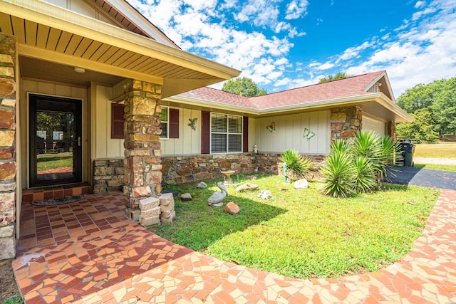 doorway to property featuring stone siding, board and batten siding, an attached garage, and driveway