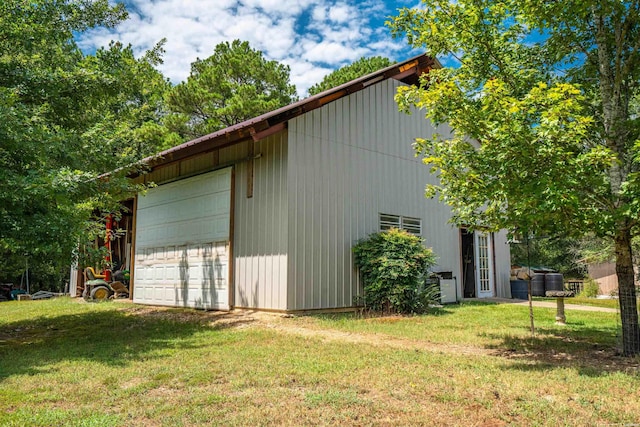 view of property exterior featuring a detached garage, a lawn, and an outdoor structure