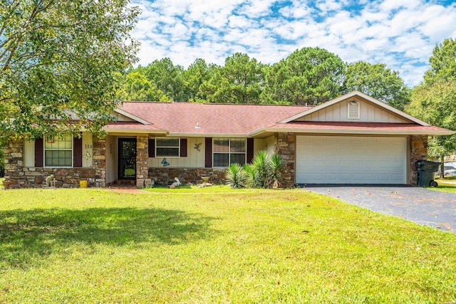 ranch-style home featuring driveway, stone siding, a front yard, a shingled roof, and a garage