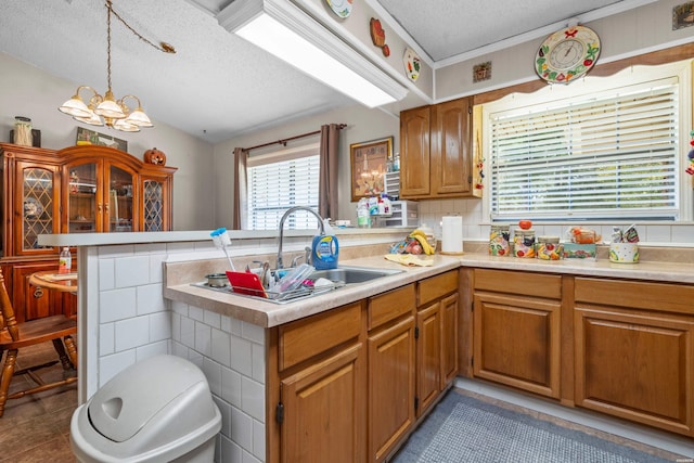 kitchen featuring a notable chandelier, a peninsula, light countertops, and a sink