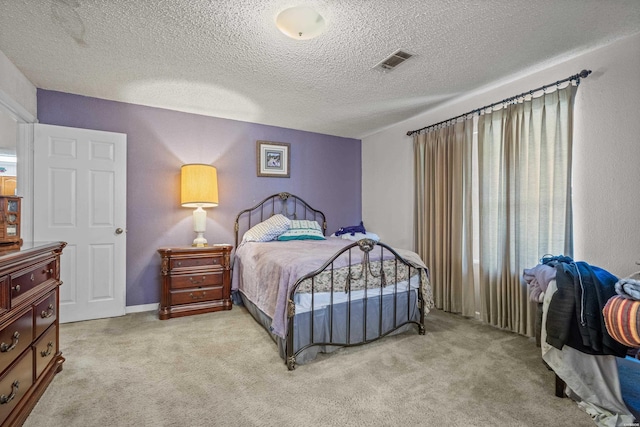 bedroom with visible vents, light colored carpet, and a textured ceiling