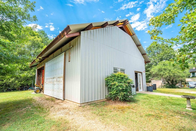 view of side of property with a lawn, a detached garage, and an outdoor structure