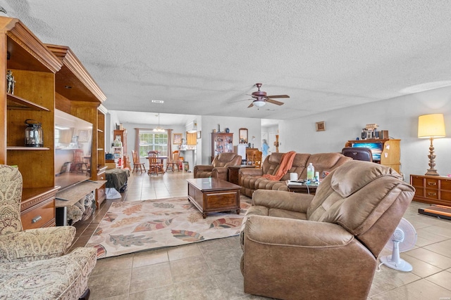 living room featuring tile patterned flooring, a ceiling fan, and a textured ceiling