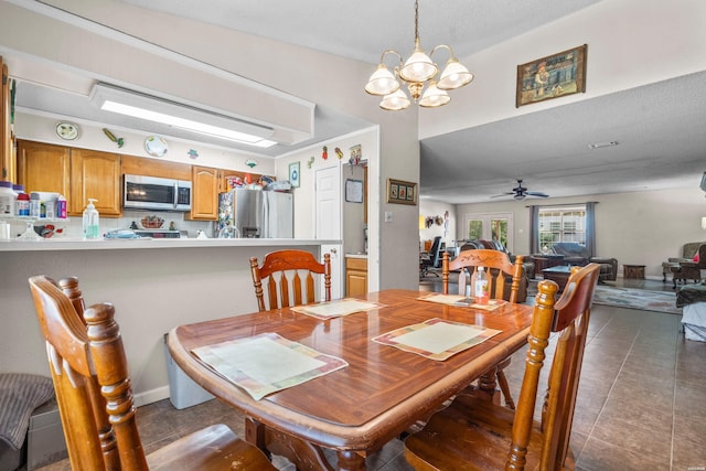 dining area featuring dark tile patterned floors and ceiling fan with notable chandelier