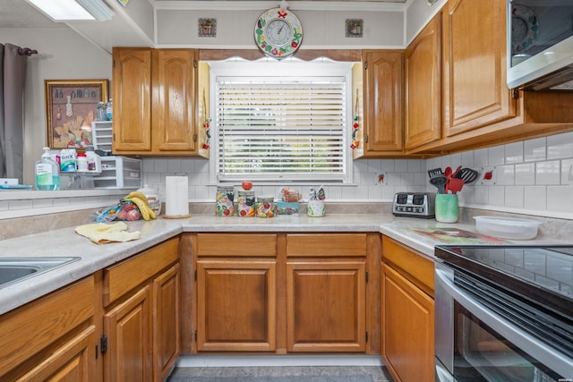 kitchen with brown cabinetry, appliances with stainless steel finishes, tasteful backsplash, and light countertops