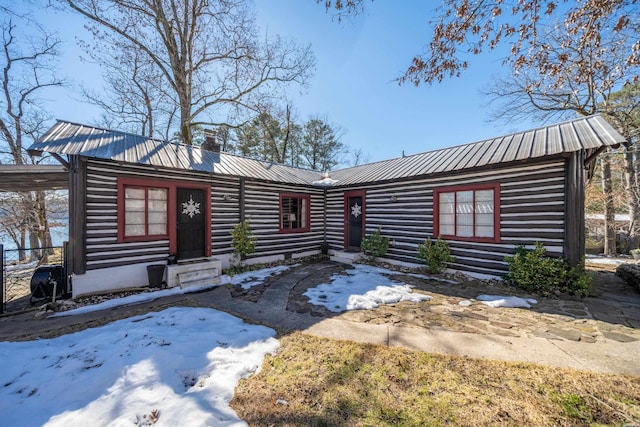 log cabin with entry steps, a chimney, and metal roof