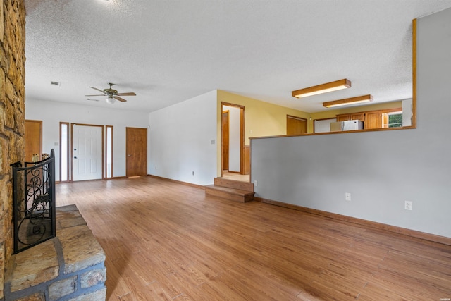 unfurnished living room featuring a fireplace, visible vents, a ceiling fan, a textured ceiling, and light wood-type flooring