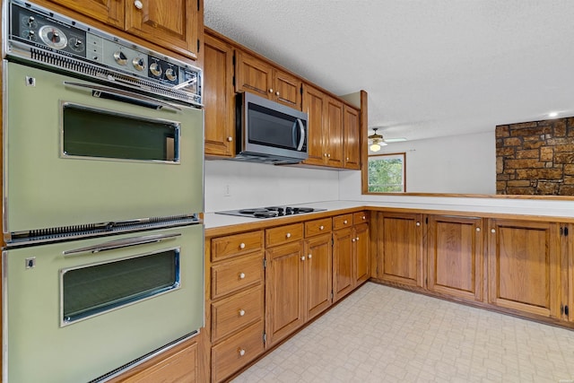 kitchen with brown cabinets, stainless steel microwave, light countertops, and white double oven