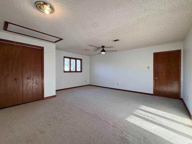 unfurnished bedroom featuring light carpet, attic access, visible vents, and baseboards