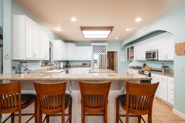 kitchen with white cabinetry, stainless steel appliances, a sink, and a kitchen breakfast bar