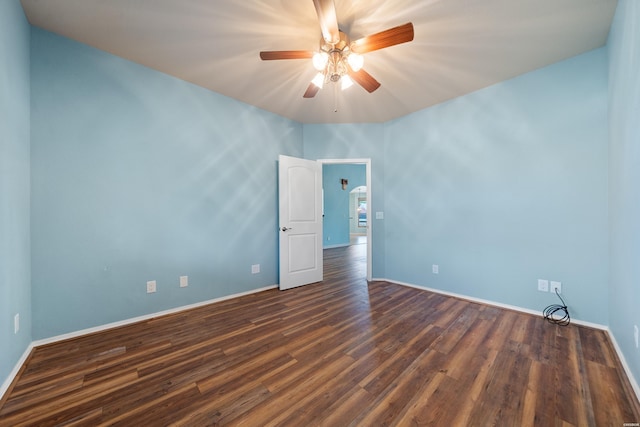 empty room with ceiling fan, dark wood finished floors, and baseboards