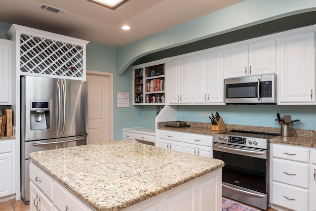 kitchen featuring a kitchen island, visible vents, stainless steel appliances, and light stone counters