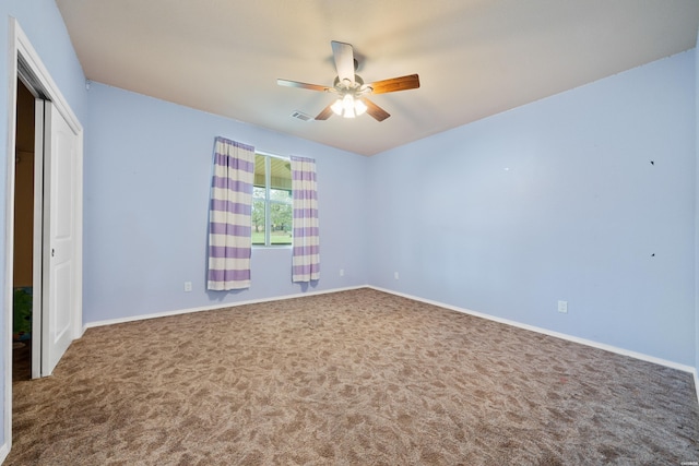 carpeted empty room with visible vents, ceiling fan, and baseboards