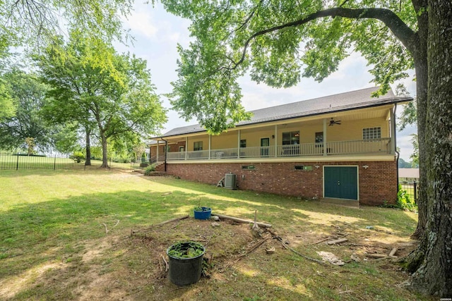 back of property with ceiling fan, central AC unit, brick siding, fence, and a yard