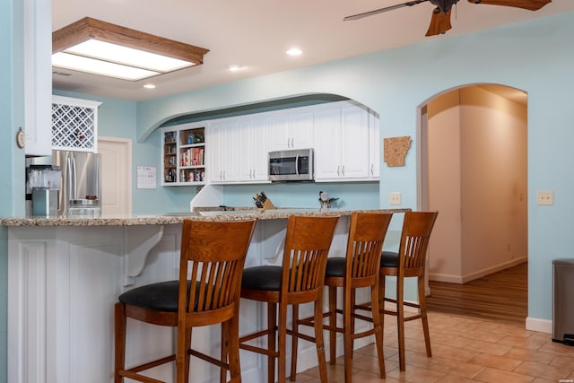 kitchen featuring recessed lighting, stainless steel appliances, a peninsula, white cabinets, and open shelves