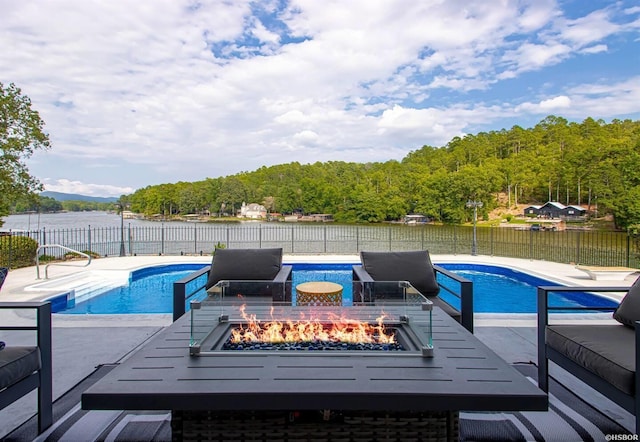 view of swimming pool featuring a patio, an outdoor fire pit, a water view, fence, and a fenced in pool