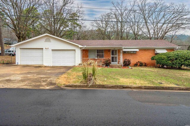 ranch-style home featuring driveway, an attached garage, covered porch, a front lawn, and brick siding