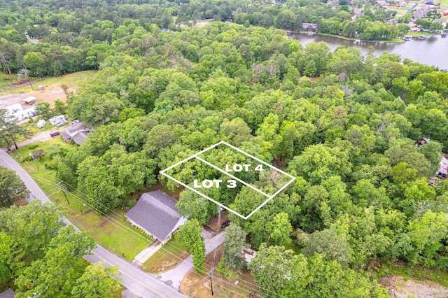 birds eye view of property with a water view and a wooded view