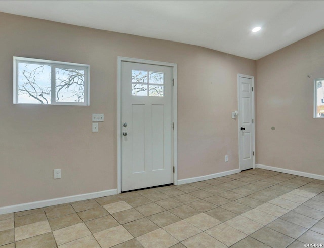 foyer featuring baseboards, plenty of natural light, and light tile patterned flooring