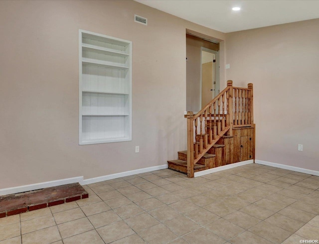 empty room with visible vents, baseboards, built in features, stairs, and light tile patterned floors