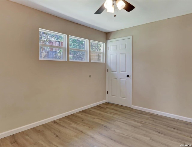 empty room with a ceiling fan, light wood-style floors, and baseboards