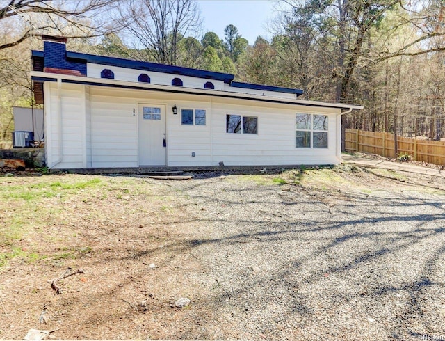 view of front of property featuring cooling unit, a chimney, and fence