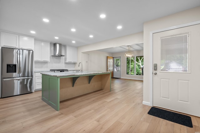 106 Grissom Trl, Hot Springs, AR 71913 - kitchen with stainless steel refrigerator with ice dispenser, wall chimney exhaust hood, white cabinetry, light wood-style floors, and a kitchen bar