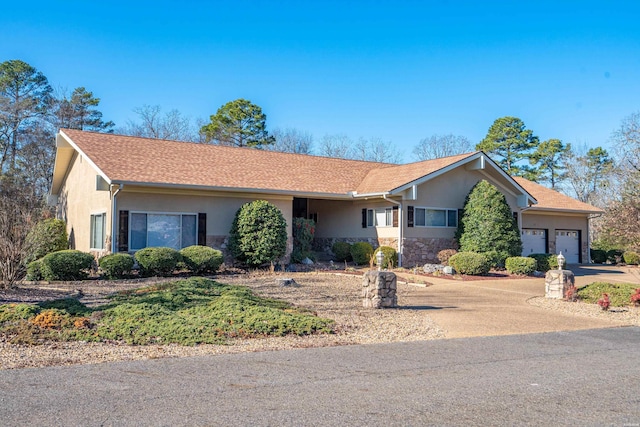 ranch-style house featuring stone siding, an attached garage, driveway, and stucco siding