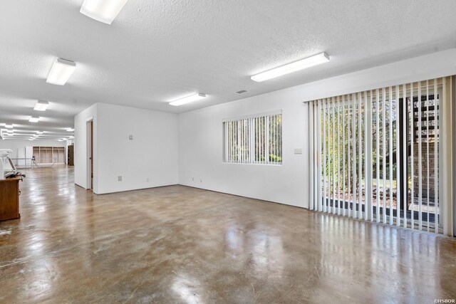 unfurnished room with concrete floors, plenty of natural light, and a textured ceiling