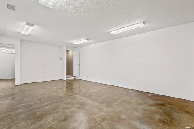 spare room featuring finished concrete flooring, visible vents, and a textured ceiling