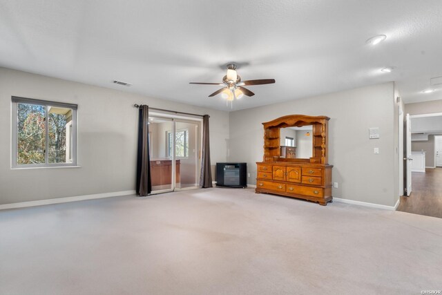 unfurnished living room with a ceiling fan, carpet flooring, visible vents, and baseboards