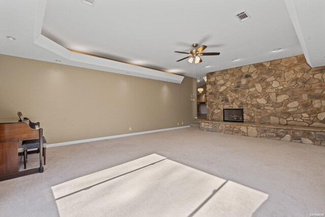 unfurnished living room with a fireplace, visible vents, a ceiling fan, light carpet, and baseboards