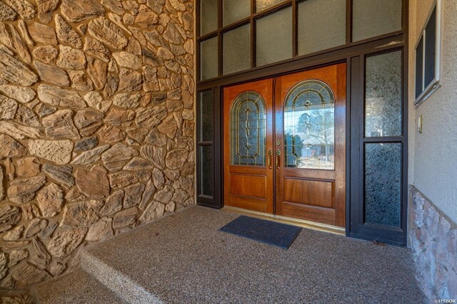 property entrance featuring stone siding and french doors