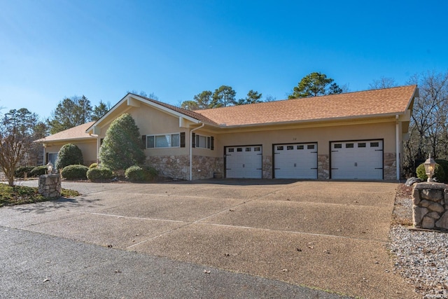 ranch-style home with stone siding, an attached garage, concrete driveway, and stucco siding