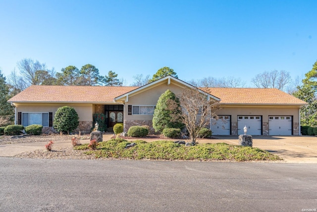 ranch-style house featuring concrete driveway, an attached garage, and stucco siding