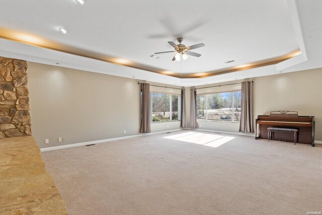 unfurnished room featuring baseboards, a tray ceiling, ceiling fan, and light colored carpet