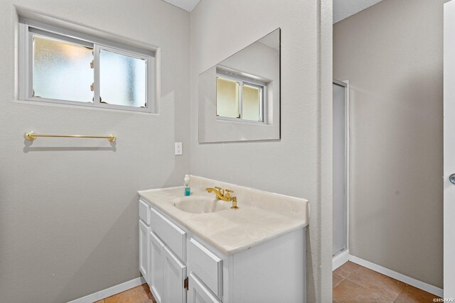 bathroom featuring baseboards, a shower stall, vanity, and a healthy amount of sunlight